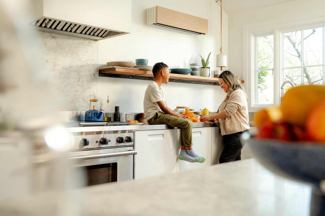 Parent and child spending time together in a bright kitchen with a ductless mini-split heat pump mounted above the counter for energy-efficient home comfort.
