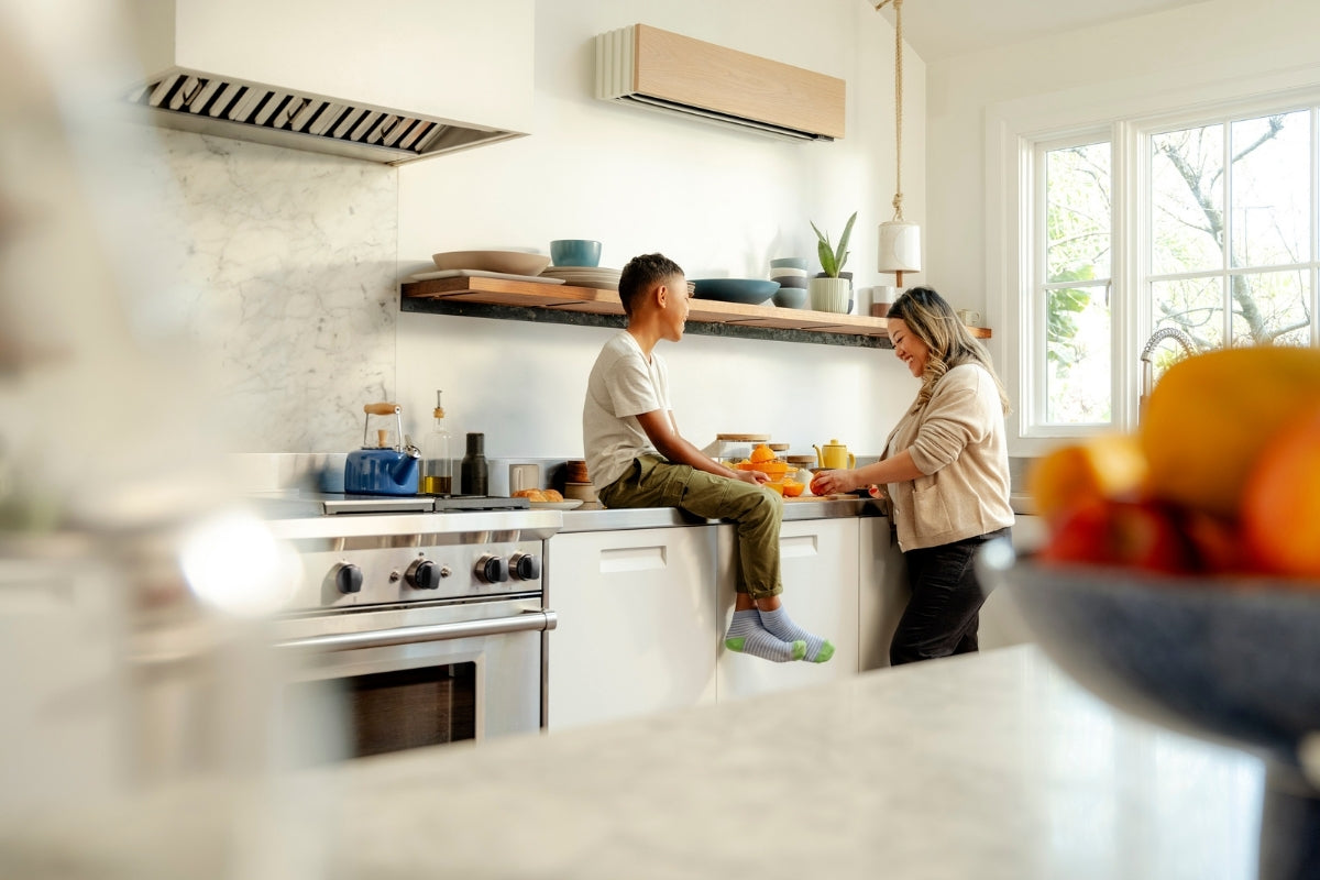 Parent and child spending time together in a bright kitchen with a ductless mini-split heat pump mounted above the counter for energy-efficient home comfort.