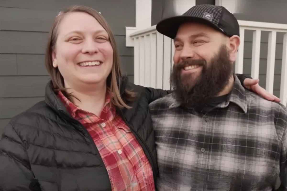Ryan and Megan stand together outside their home smiling at the camera.