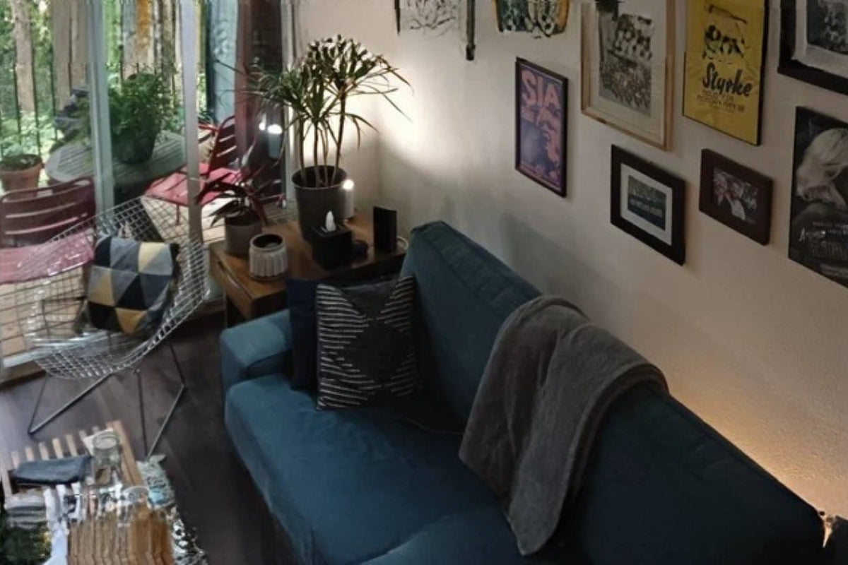A cozy living room with a couch, a chair, house plants, and prints on the wall.