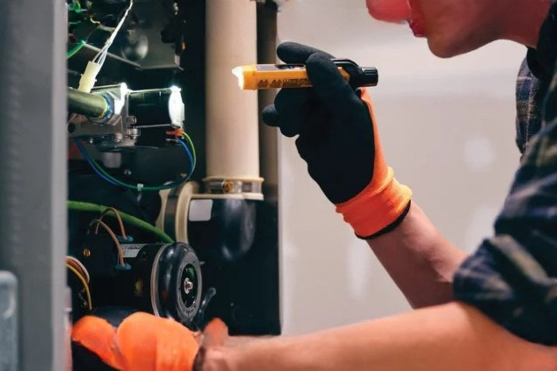 Someone holds a flashlight up to the inside of a furnace.