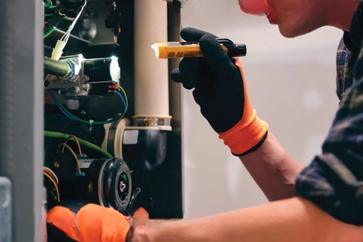 Someone holds a flashlight up to the inside of a furnace.