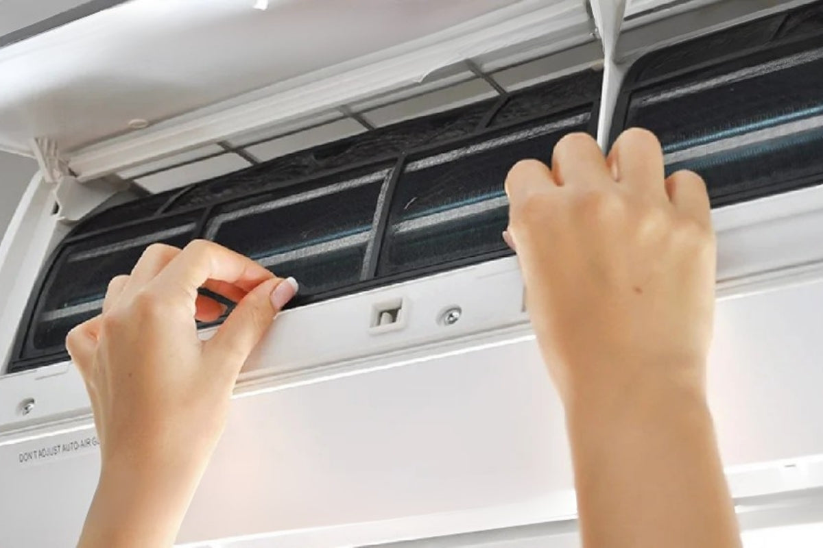 Someone's hands reaching up to adjust a heat pump.