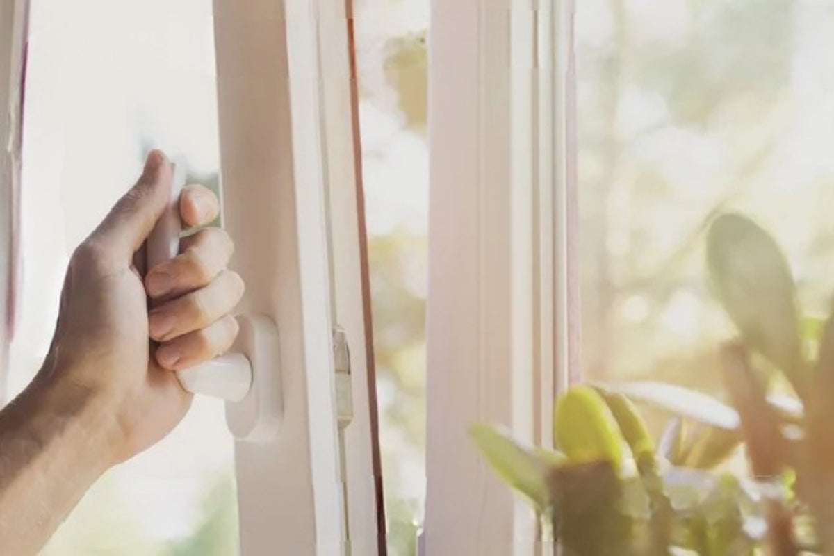A person opens a vinyl window using the latch.