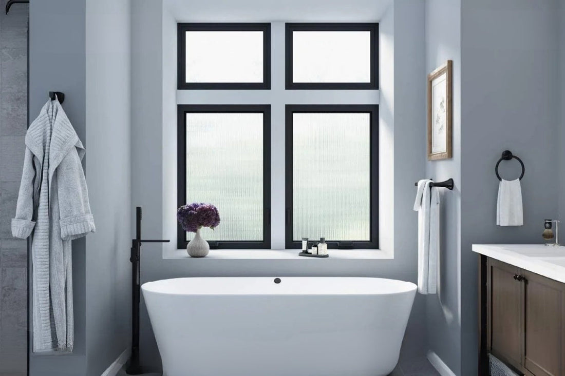 A claw foot bath tub centered in a bathroom with 4 windows behind it.